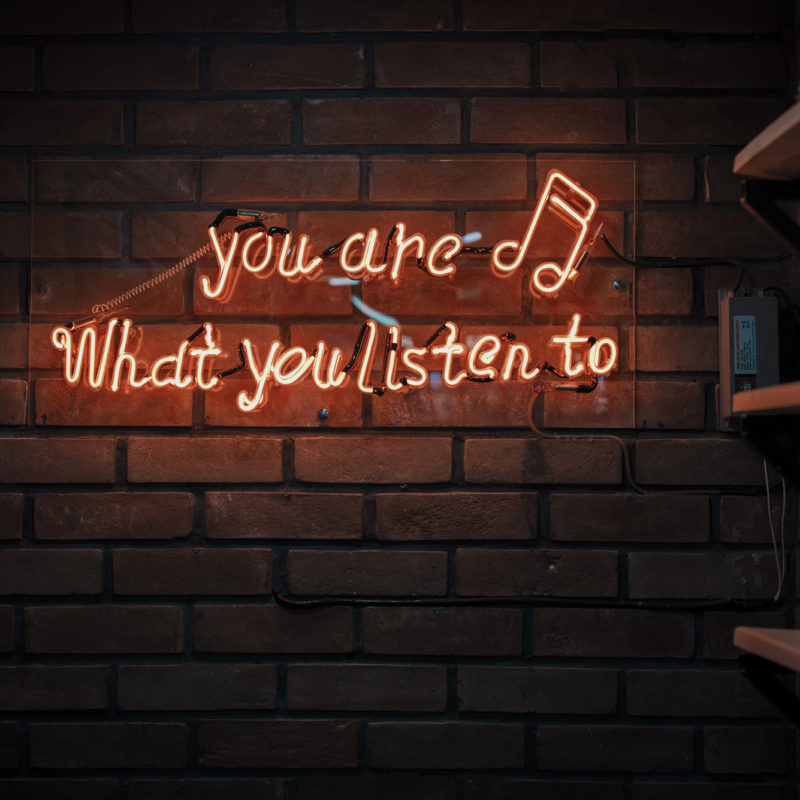 neon sign on brick wall that says "you are what you listen to"