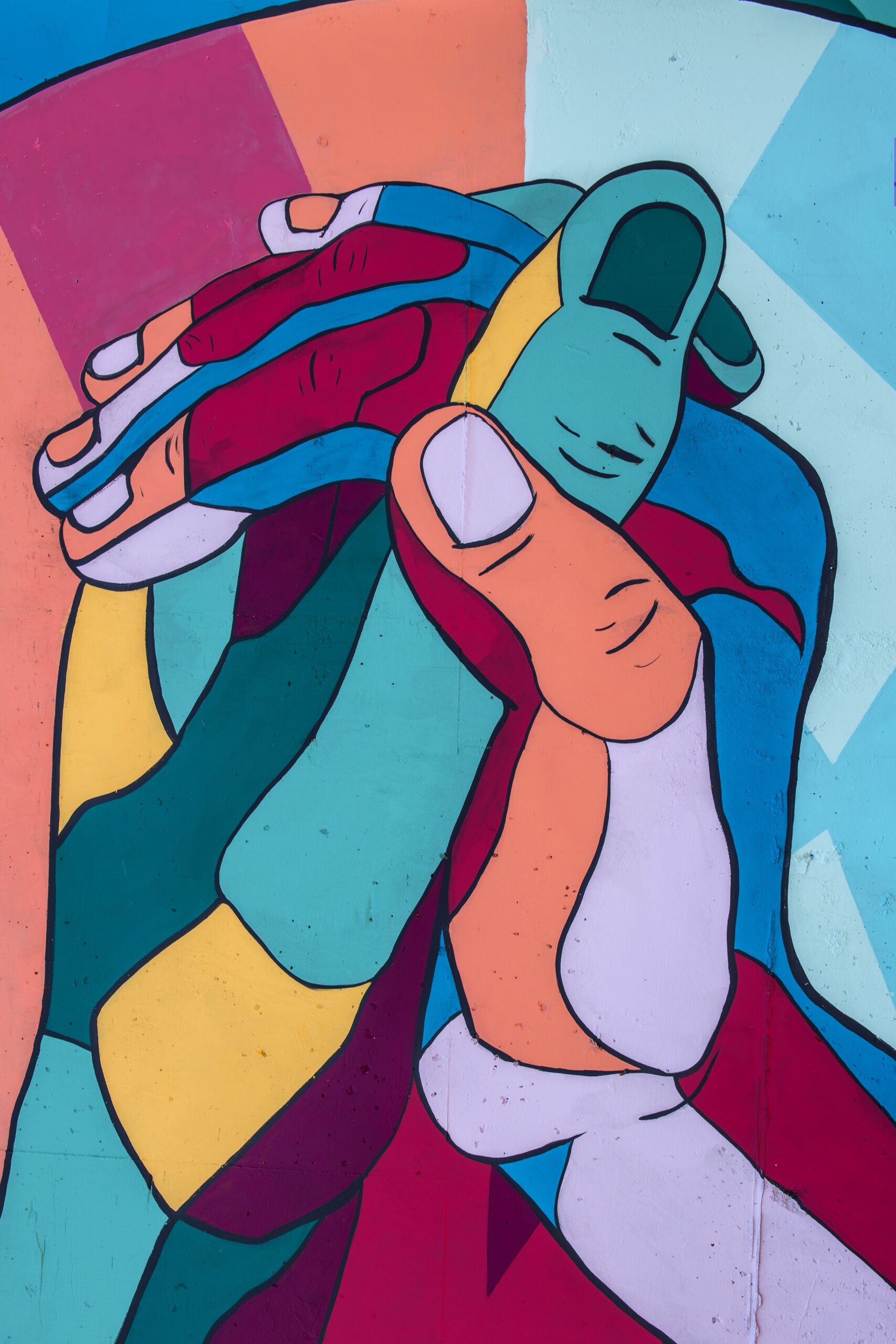 Mural of two hands intertwining, done in a geometric, multicolored style