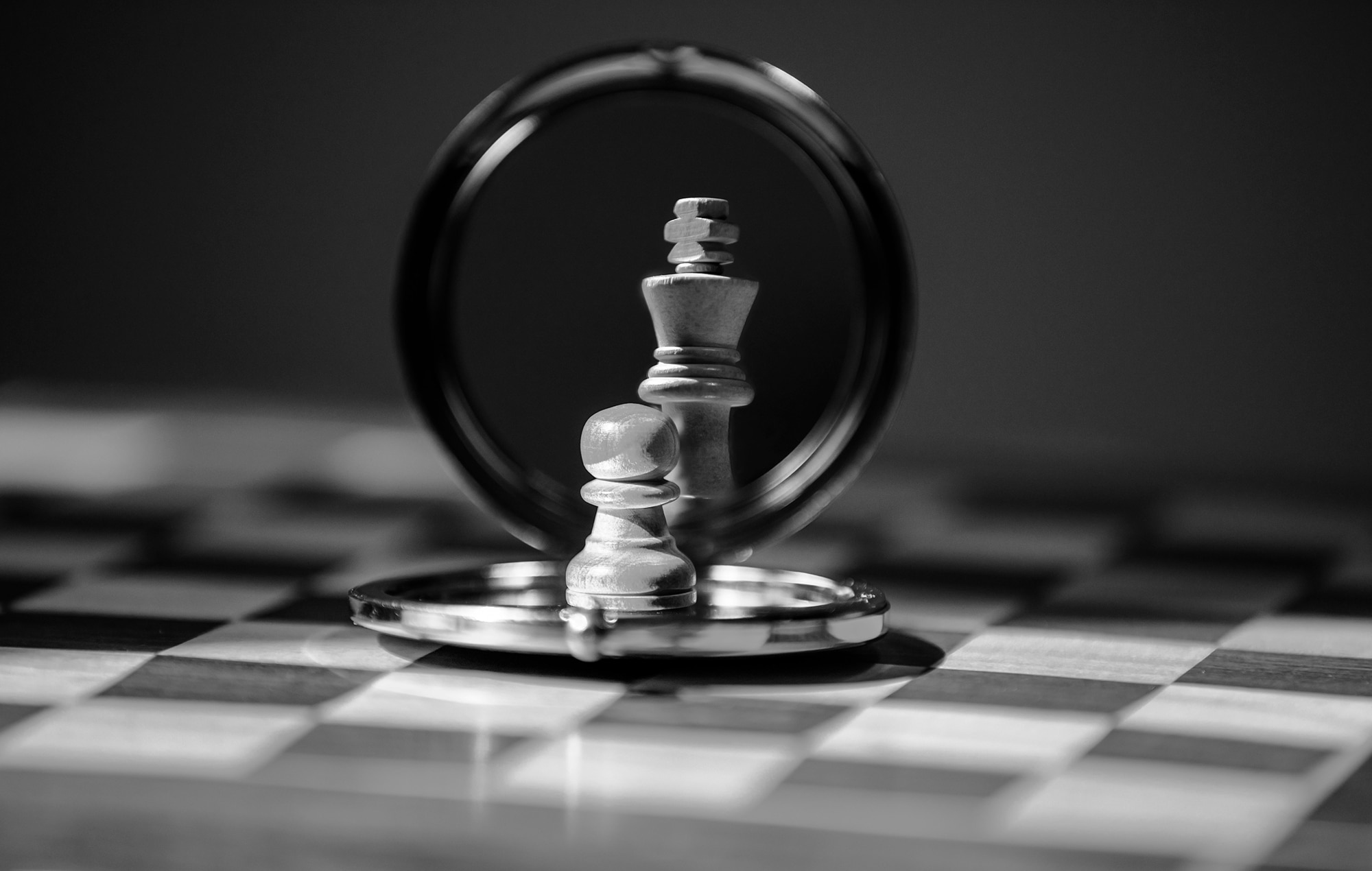 A pawn chess piece looking into a mirror. The reflection shows a king chess piece.