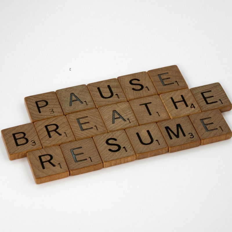 Wooden Scarbble tiles that says "Pause, Breathe, Resume".